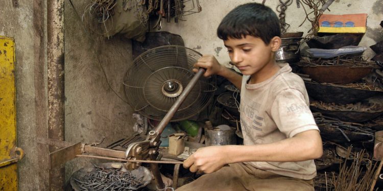 Dhiyaa Mohammed, 12, pauses from his work in a blacksmith shop owned by his father in Baghdad, the capital. Dhiyaa says, 'I studied up to grade five. But I didn't like school so my father put me to work here. This is worse than school, so I plan to return to school soon.'. (Photo by: Majority World/UIG via Getty Images)