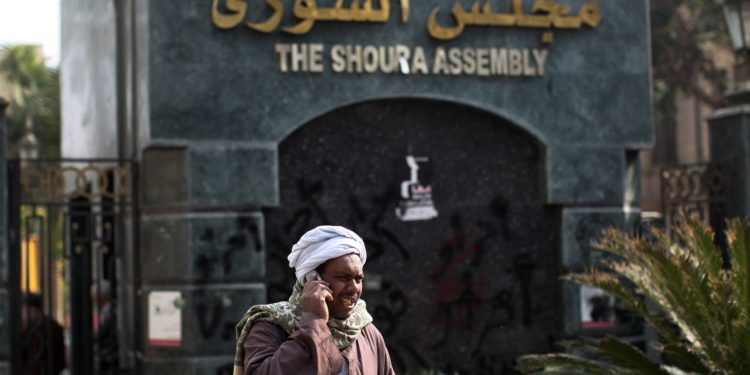 An Egyptian man talks on his mobile phone outside the Shura Council, the upper house of parliament where the Constituent Assembly drafted the country's new constitution, on December 26, 2012 in Cairo. Egyptian President Mohamed Morsi has signed into law a new constitution voted in despite weeks of opposition protests, but he was left facing an economic crisis and international disquiet over his rule. AFP PHOTO/MAHMUD HAMS