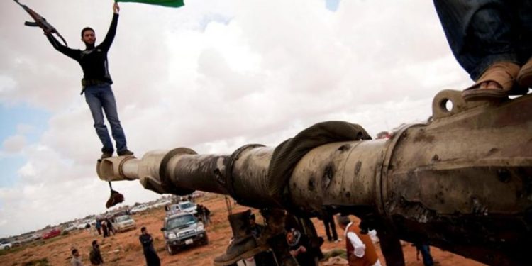 مسلح ليبي يحمل علم الاستقلال أعلى فوهة دبابة (أرشيفية)