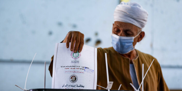 A man, mask-clad due to the COVID-19 coronavirus pandemic, casts his vote at a polling station in the Talibeya district of Giza, the twin-city of Egypt's capital, on October 24, 2020, while voting in the first stage of the lower house elections. - Polling stations opened in Egypt for parliamentary elections in which there was little doubt of a sweeping victory for supporters of hardline President Abdel Fattah al-Sisi. Some 63 million voters out of Egypt's more than 100 million people are eligible to elect 568 of the 596 lawmakers in the lower house, widely seen as a rubber-stamp body for executive policies. (Photo by Khaled DESOUKI / AFP)