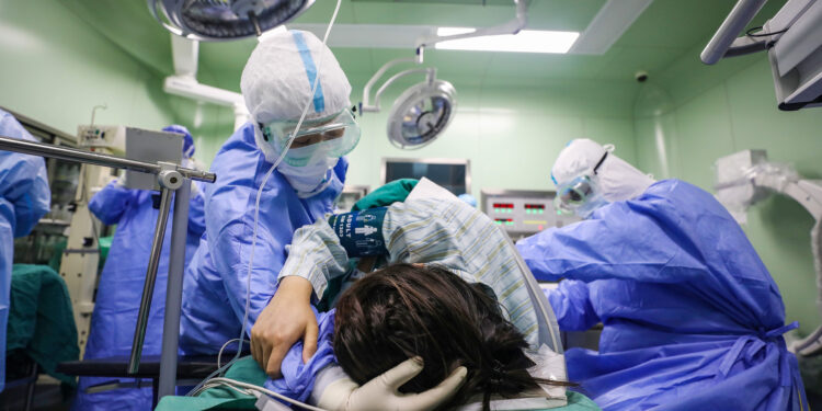 This photo taken on March 7, 2020 shows a doctor comforting a pregnant woman, infected by the COVID-19 coronavirus, before her caesarean section at a gynaecology and obstetrics isolation ward in Xiehe hospital in Wuhan in China's central Hubei province. - China on March 8 reported its lowest number of new coronavirus infections since January, with nearly all the 44 new cases in the outbreak epicentre Wuhan. (Photo by STR / AFP) / China OUT