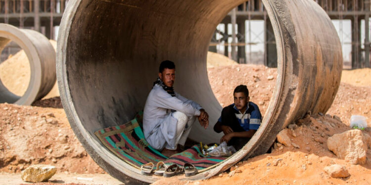 عمالان يستريحان داخل أنبوب خرساني أثناء اختبائهم من أشعة الشمس في موقع بناء في مشروع "العاصمة الإدارية الجديدة" - وكالات
