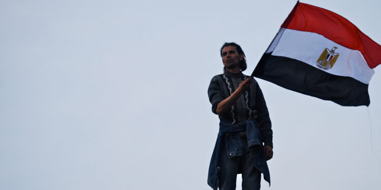 شاب يرفع علم مصر في أحداث ثورة يناير 2011 (وكالات)
