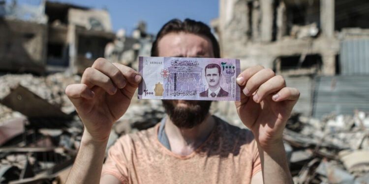 مواطن سوري يحمل عملة من فئة 2000 ليرة (وكالات)
