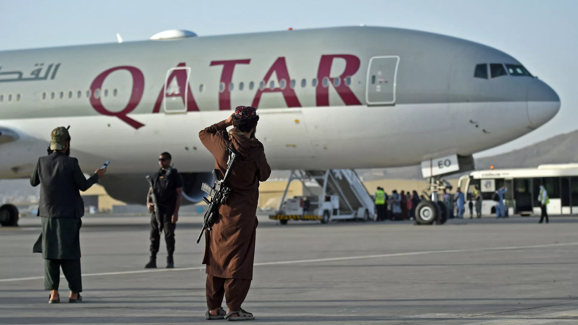 أفراد الأمن القطريون (يسار) ومقاتلو طالبان يقفون في حراسة أثناء صعود الركاب على متن طائرة الخطوط الجوية القطرية، 9 سبتمبر/ أيلول 2021. (وكالات)