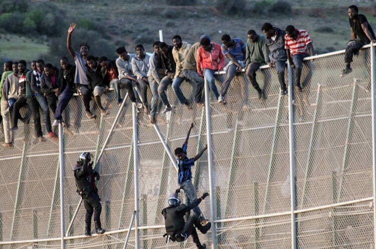 مهاجرون أفارقة يعبرون الحاجز الحدودي بين المغرب وإسبانيا (وكالات)