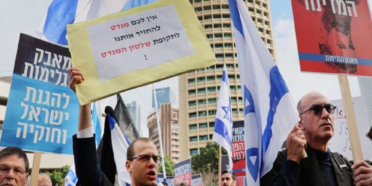 رجل يحمل لافتة كتب عليها بالعبرية تقول "لن ندعك تعود إلى أيام الانتداب البريطاني الخوالي" خلال مظاهرة للمحامين ضد خطط الحكومة الإسرائيلية المثيرة للجدل لإصلاح النظام القضائي- محكمة العدل في 12 يناير/ كانون الثاني 2023