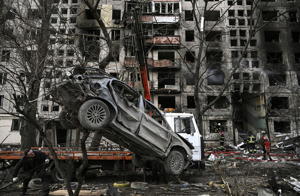 رافعة تزيل سيارة مدمرة من أمام مبنى سكني مدمر بعد قصفها من قبل روسيا، في كييف بأوكرانيا، 14 مارس/ آذار 2022.(وكالات)