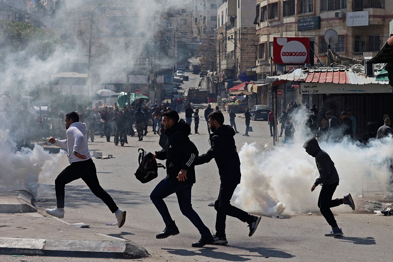 فلسطينيون يهربون من قنابل الغاز المسيل للدموع في نابلس (وكالات)