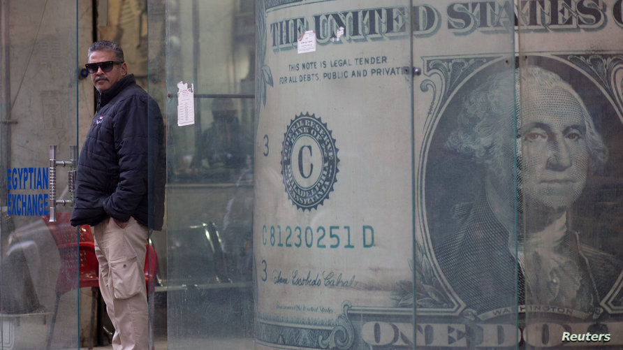 حارس أمن يقف أمام إعلان لمكتب صرافة يظهر صورة الدولار الأمريكي في القاهرة، مصر، 18 يناير/ كانون الثاني 2023. (رويترز)