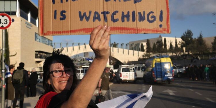 متظاهرة تحمل لافتة خلال تجمع خارج البرلمان الإسرائيلي في القدس المحتلة يوم 27 مارس/ آذار 2023- وكالات