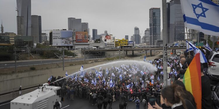 الشرطة تستخدم خراطيم المياه لتفريق المتظاهرين الذين أغلقوا الطريق السريع خلال احتجاج على خطط حكومة رئيس الوزراء بنيامين نتنياهو لإصلاح النظام القضائي في تل أبيب ، إسرائيل ، 23 مارس 2023 (AP Photo / Oded Balilty)