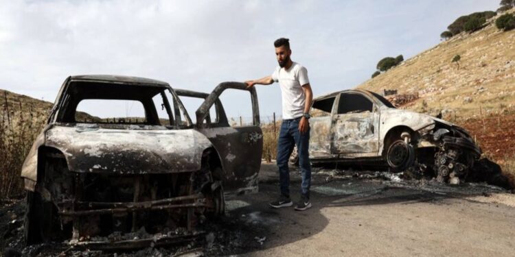 فلسطيني يتفقد سيارات أحرقها مستوطنون إسرائيليون في قرية المغير شرقي مدينة رام الله المحتلة في الضفة الغربية- 26 مايو/ أيار 2023-  AFP