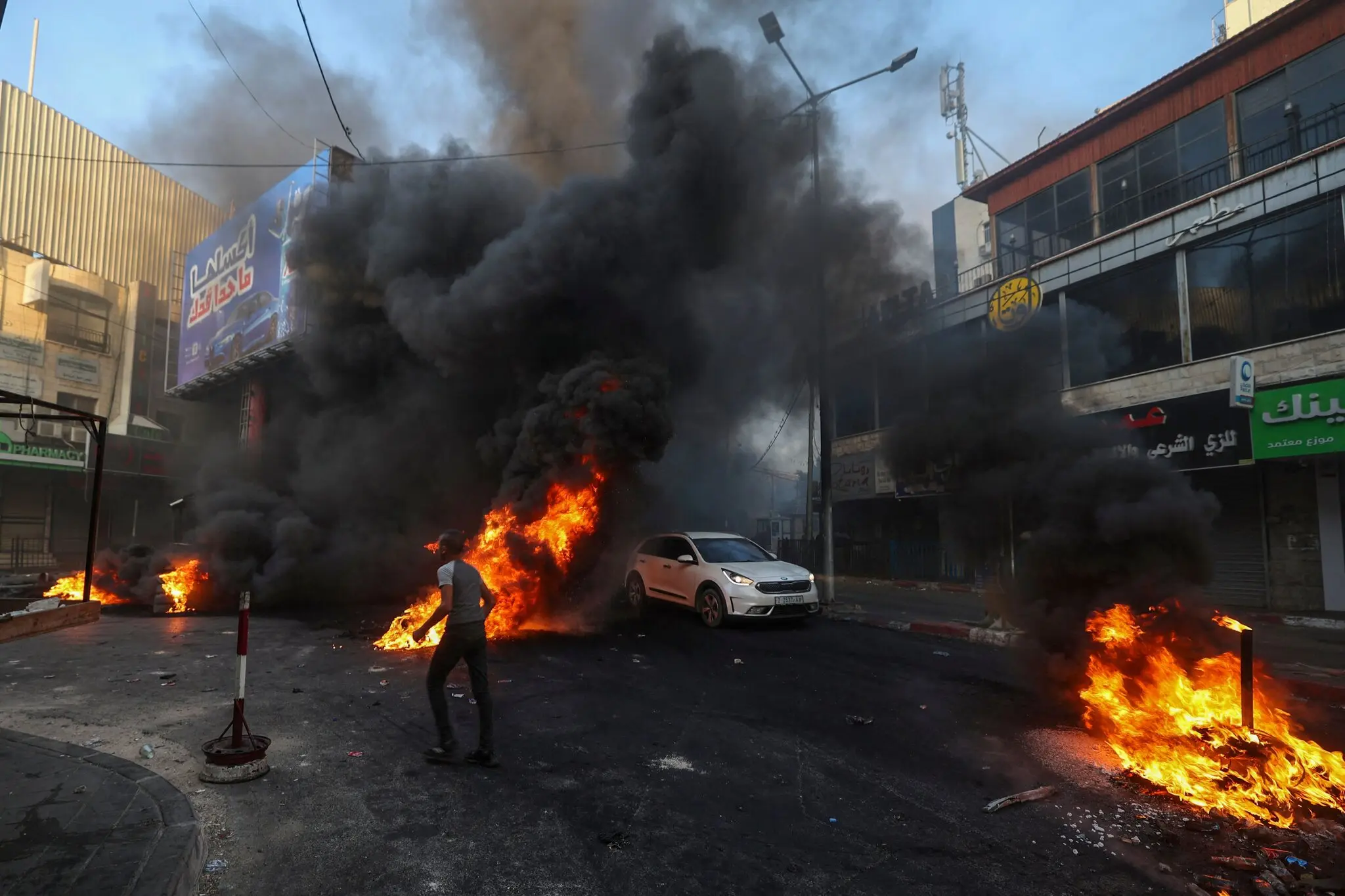 (فلسطينيون يحرقون الإطارات بعد بدء الغارة الإسرائيلية - الصورة: فرانس برس)