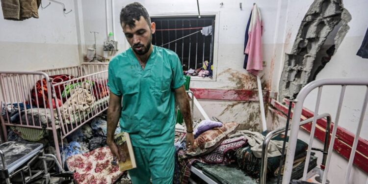 رجل يتفقد الأضرار في إحدى الغرف بعد القصف الإسرائيلي على مستشفى ناصر بخان يونس ( وكالات)