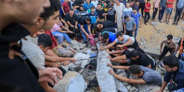 فلسطينيون يبحثون عن ناجين محاصرين تحت أنقاض مبنى دمر في غارة جوية إسرائيلية في خان يونس (وكالات)